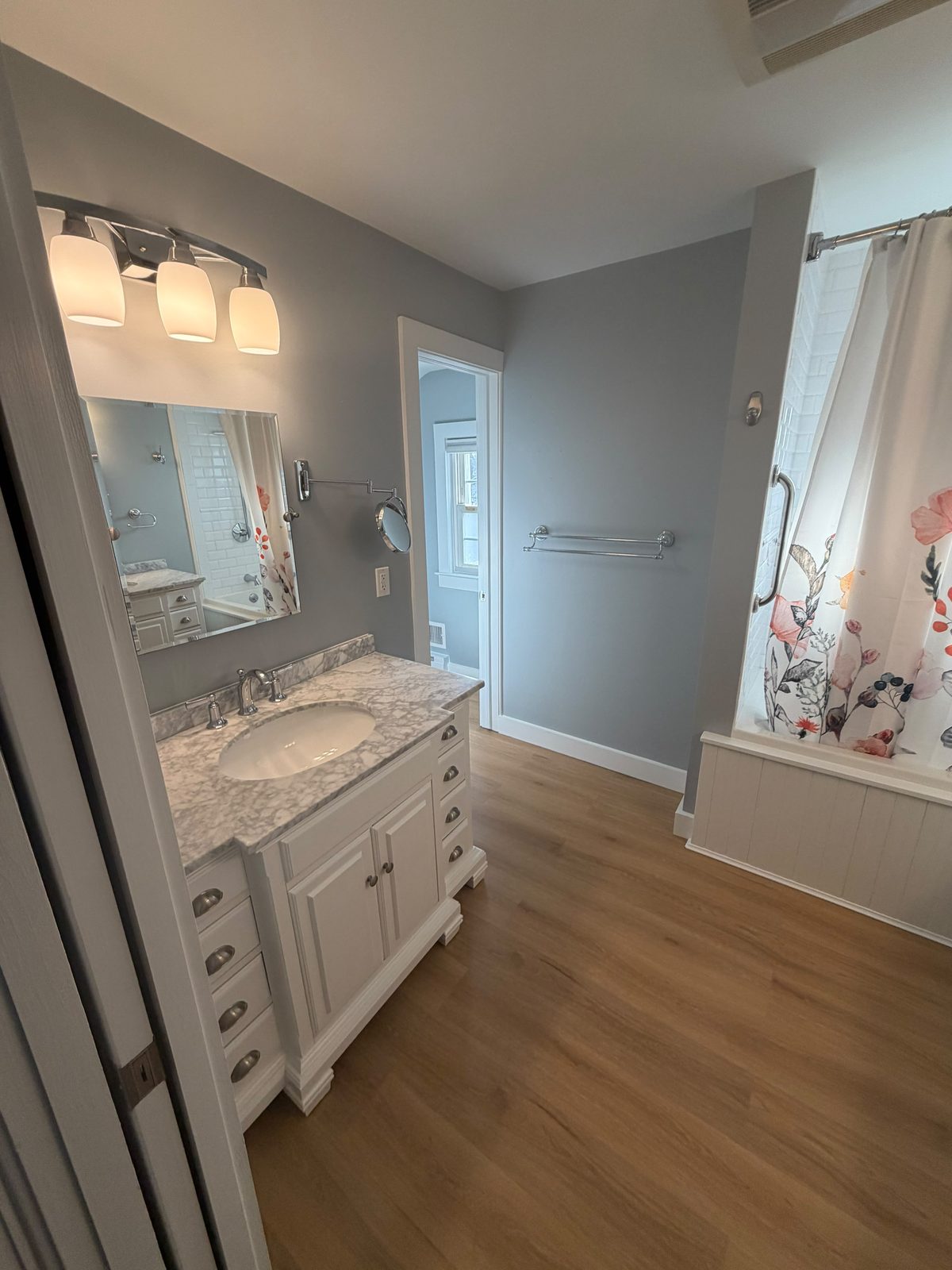 Remodeled bathroom with marble-top vanity and hardwood floor